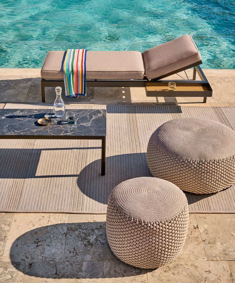 Zwei beige Pouf Hocker von Weishäupl für den Innen- und Außenbereich auf einer Terrasse.