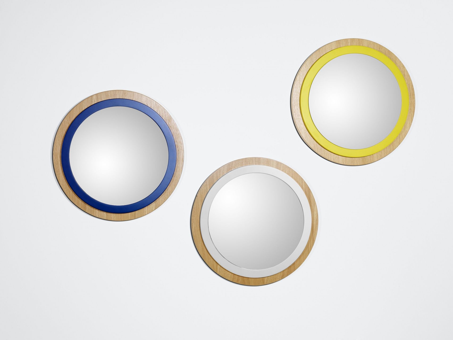 Drei runde Spiegel "Back to Bauhaus" mit farbigen Akzenten in Blau, Weiß und Gelb.