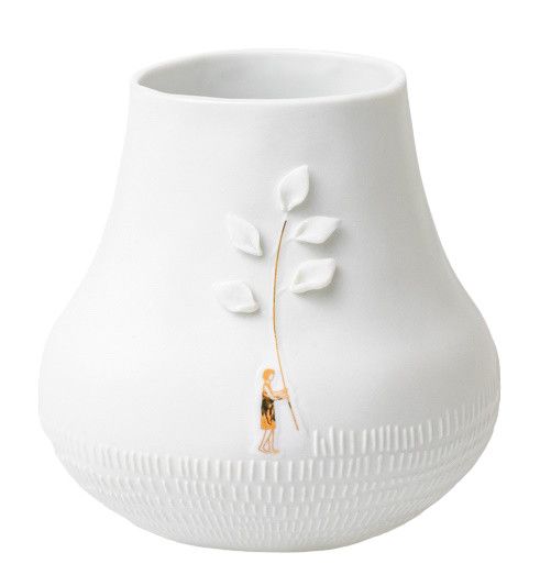 Dankbar Wiese: Nahaufnahme einer weißen Vase mit filigranem Blätterdekor und Person. Dekorative Keramik für Zuhause.