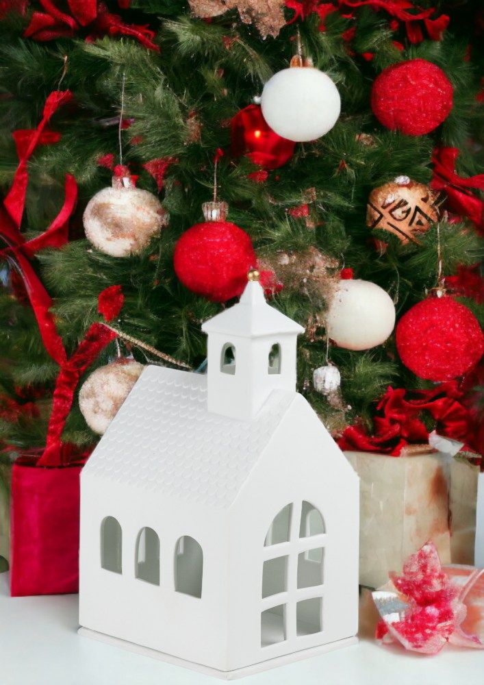 Weißes Räder Lichthaus Kapelle vor geschmücktem Weihnachtsbaum mit roten Kugeln und Geschenken.