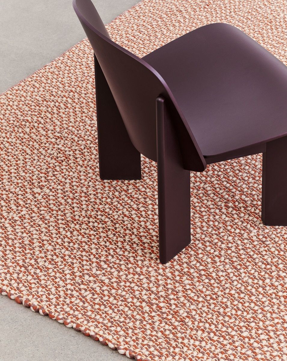 Nahaufnahme des Hay Chisel Lounge Chair Sessels in Pflaume auf einem gemusterten Teppich.