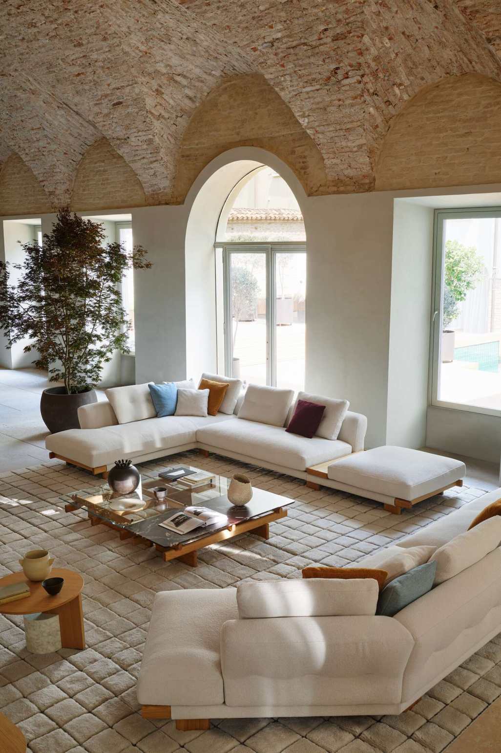 Cassina Sengu Couchtisch aus Holz und Glas vor weißer Eckcouch in hellem Wohnzimmer.