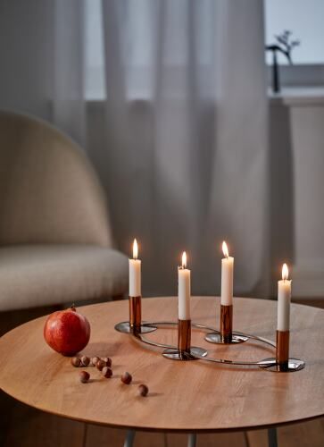 La Serena Adventskranz von Philippi mit brennenden Kerzen, Granatapfel und Nüssen auf einem Tisch.