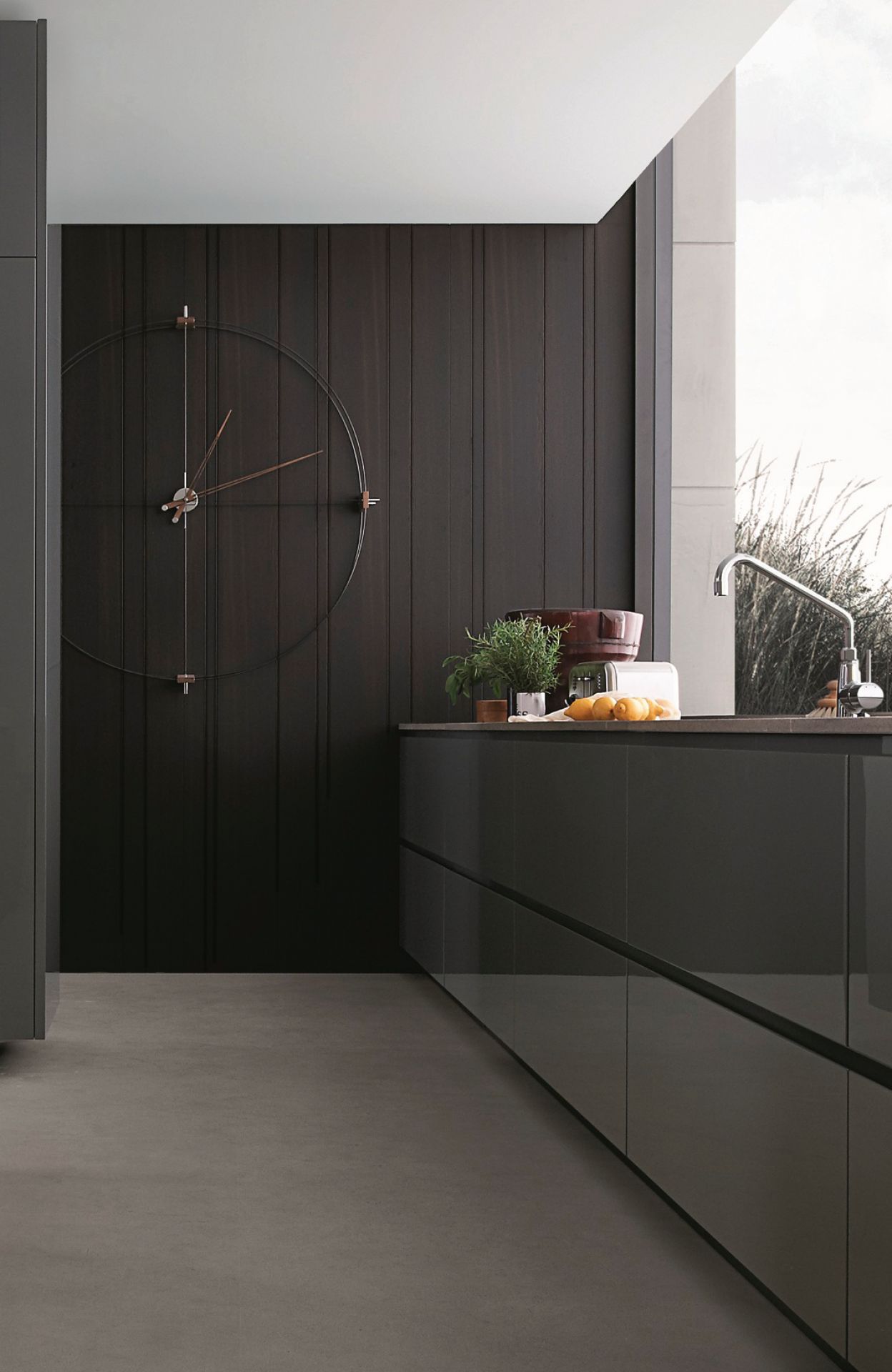 Delmori Clock Wanduhr: Moderne Wanduhr in Schwarz und Walnuss an dunkler Holzvertäfelung in Küche.