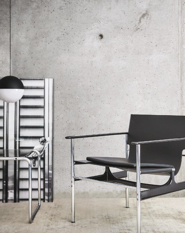 Schwarzer Pollock Sessel von Knoll International mit Chromgestell vor Betonwand. Designklassiker für stilvolles Wohnen.