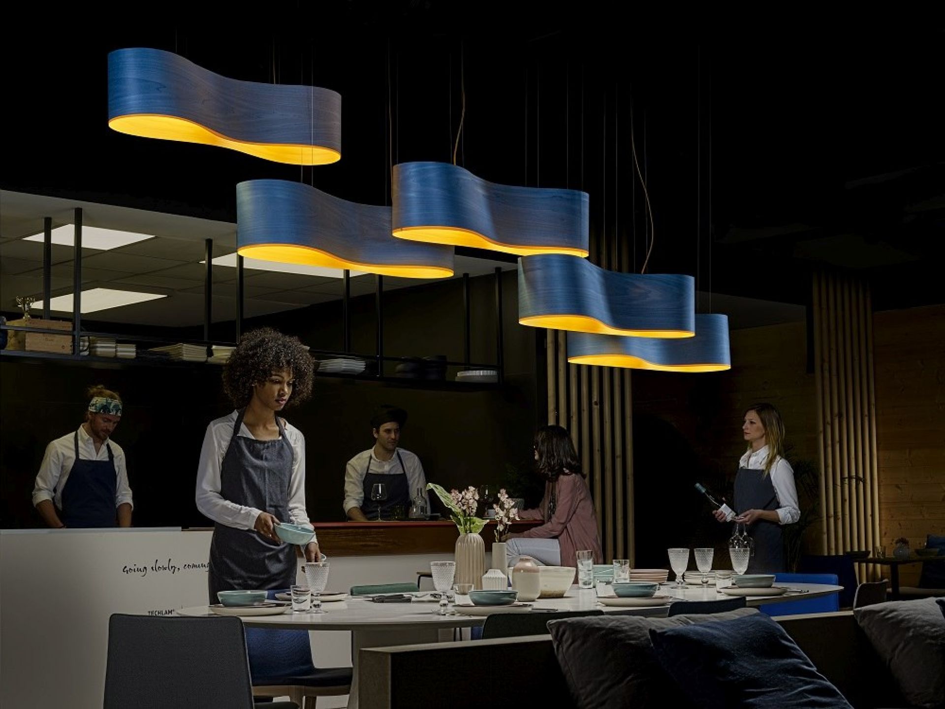 Blaue New Wave Pendelleuchten von LZF Lamps über einem gedeckten Tisch in einem Restaurant.