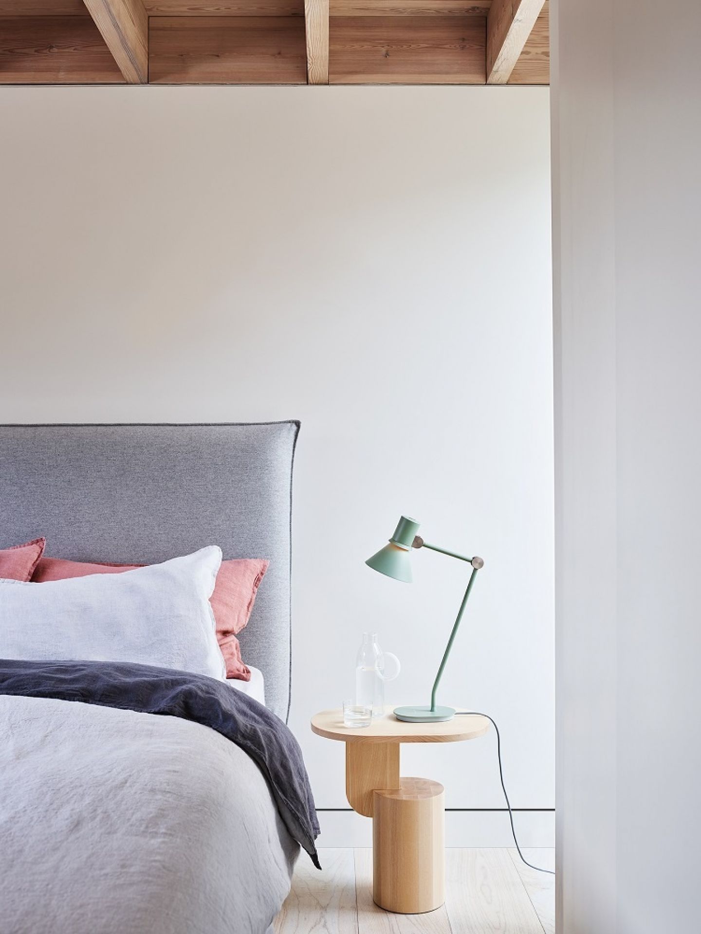 Anglepoise Type 80 Tischleuchte in Grün auf Nachttisch neben Bett mit grauer Bettwäsche.