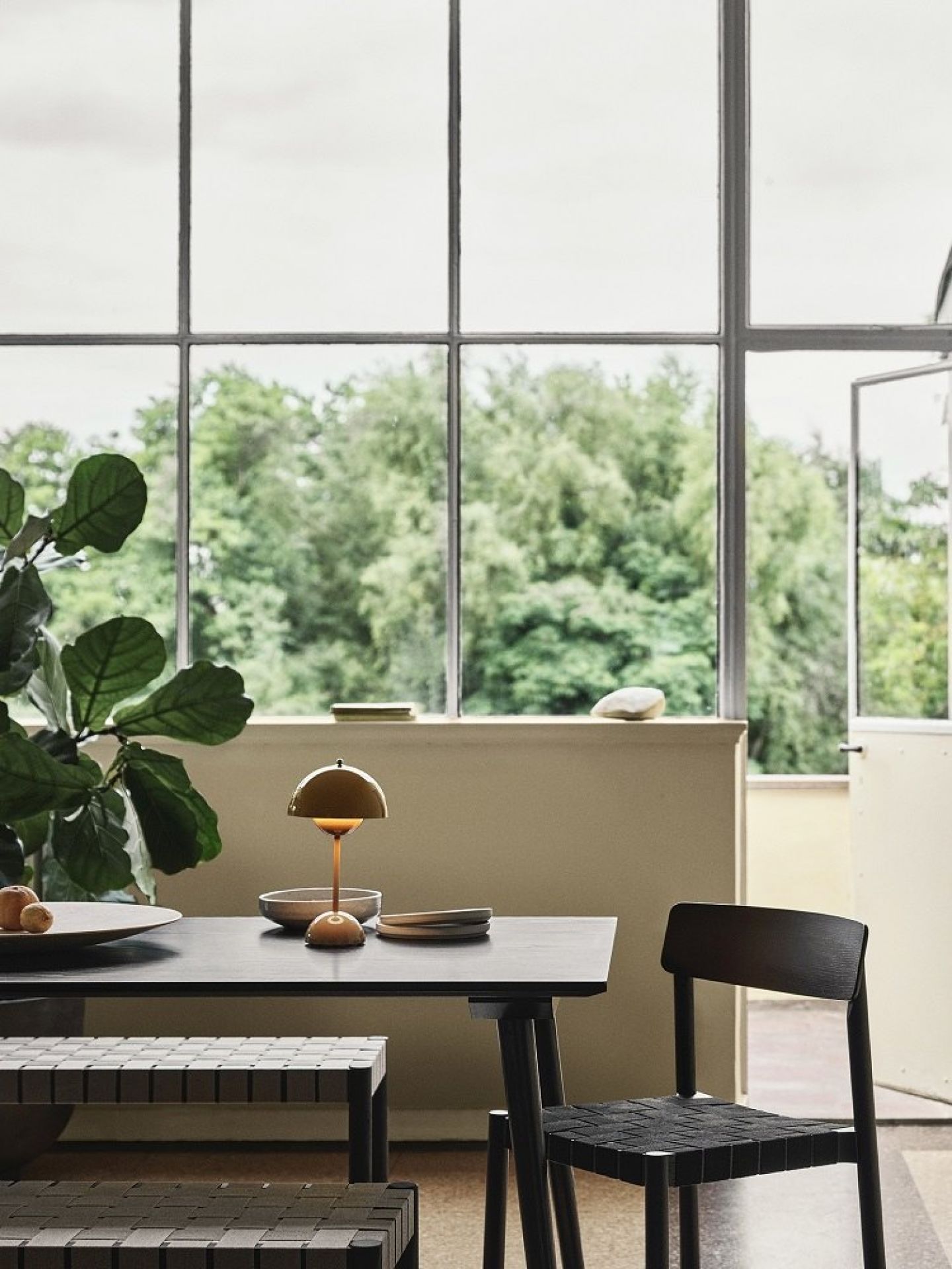 AndTradition Betty Bank TK4/TK5 aus Holz und gewebtem Textil vor Esstisch und Fenster.