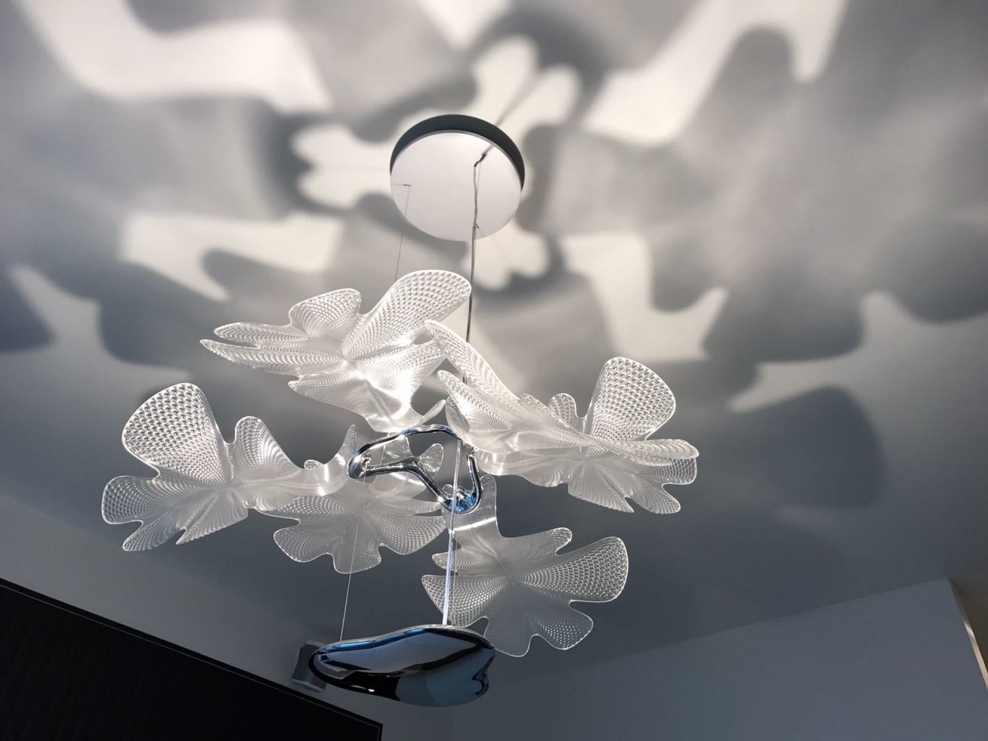 Chlorophilia Pendelleuchte von Artemide mit transparenten Diffusoren und Chromstruktur, die dekorative Schatten wirft.