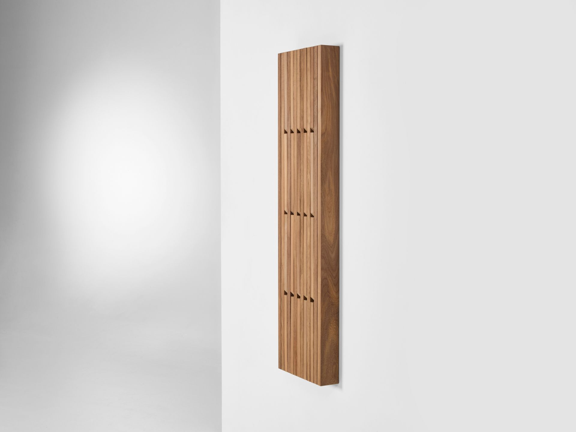Piano Wandgarderobe aus Teakholz, kleine Ausführung, an einer weißen Wand befestigt. Design Garderobe für Flur.