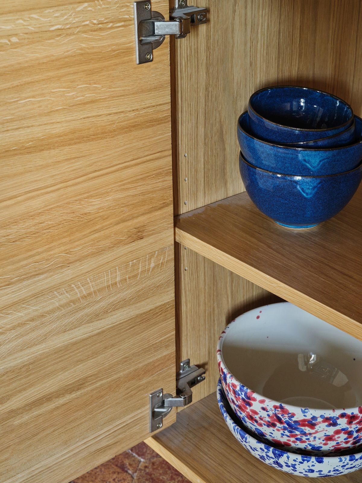 Detailaufnahme von The Hansen Family Sideboard mit Holztüren und Regalen, gefüllt mit blauen und gemusterten Schüsseln.