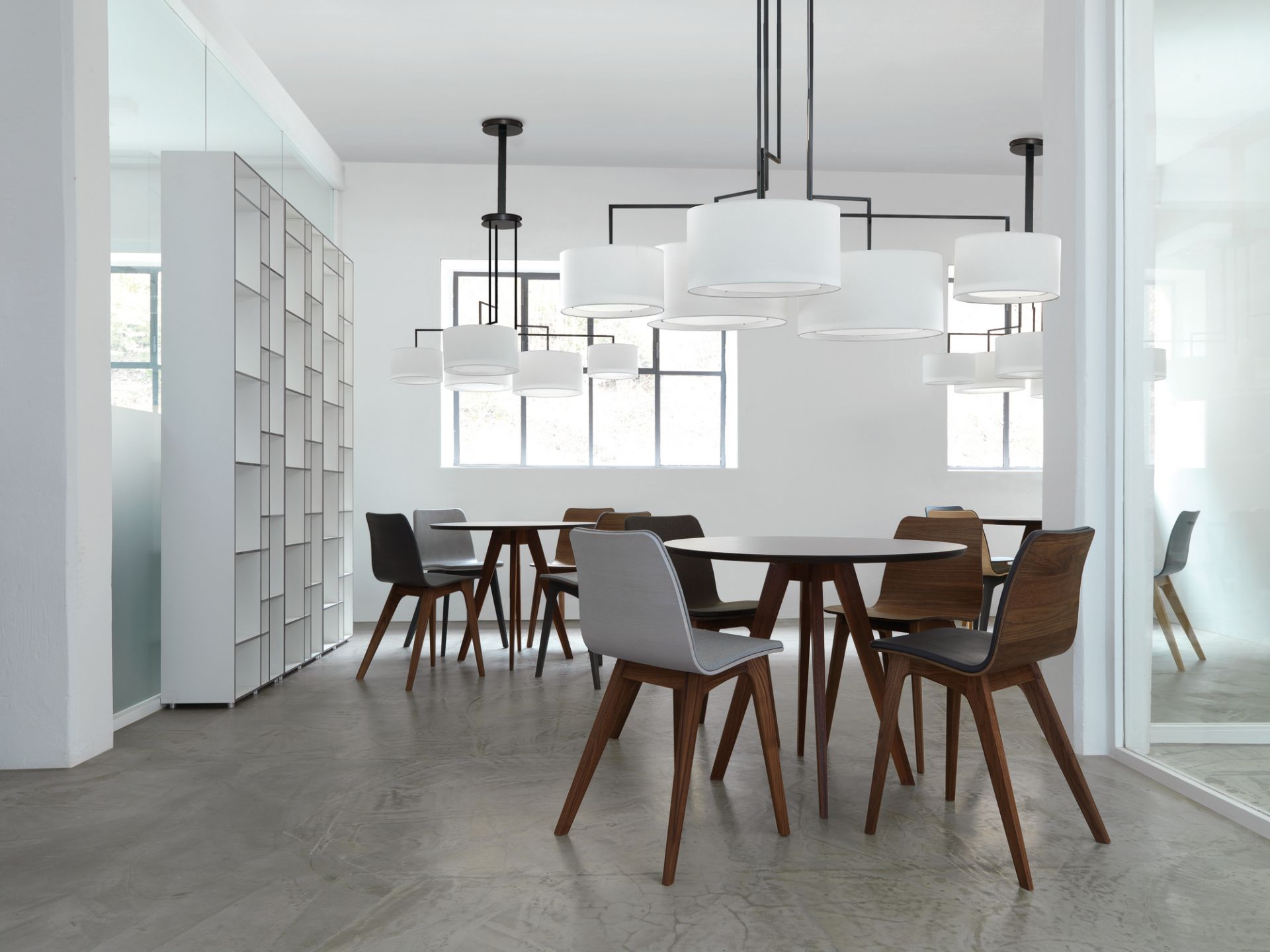 Helles Büro mit mehreren Tischen und Stühlen, im Hintergrund ein Code 1 Holzregal.