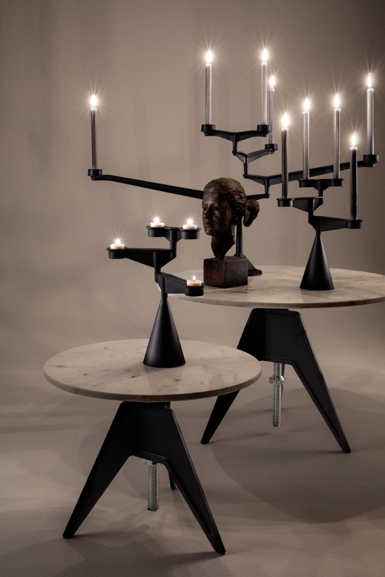Spin Candelabra Kerzenständer von Tom Dixon: Schwarzer, moderner Leuchter mit brennenden Kerzen auf Marmortischen.