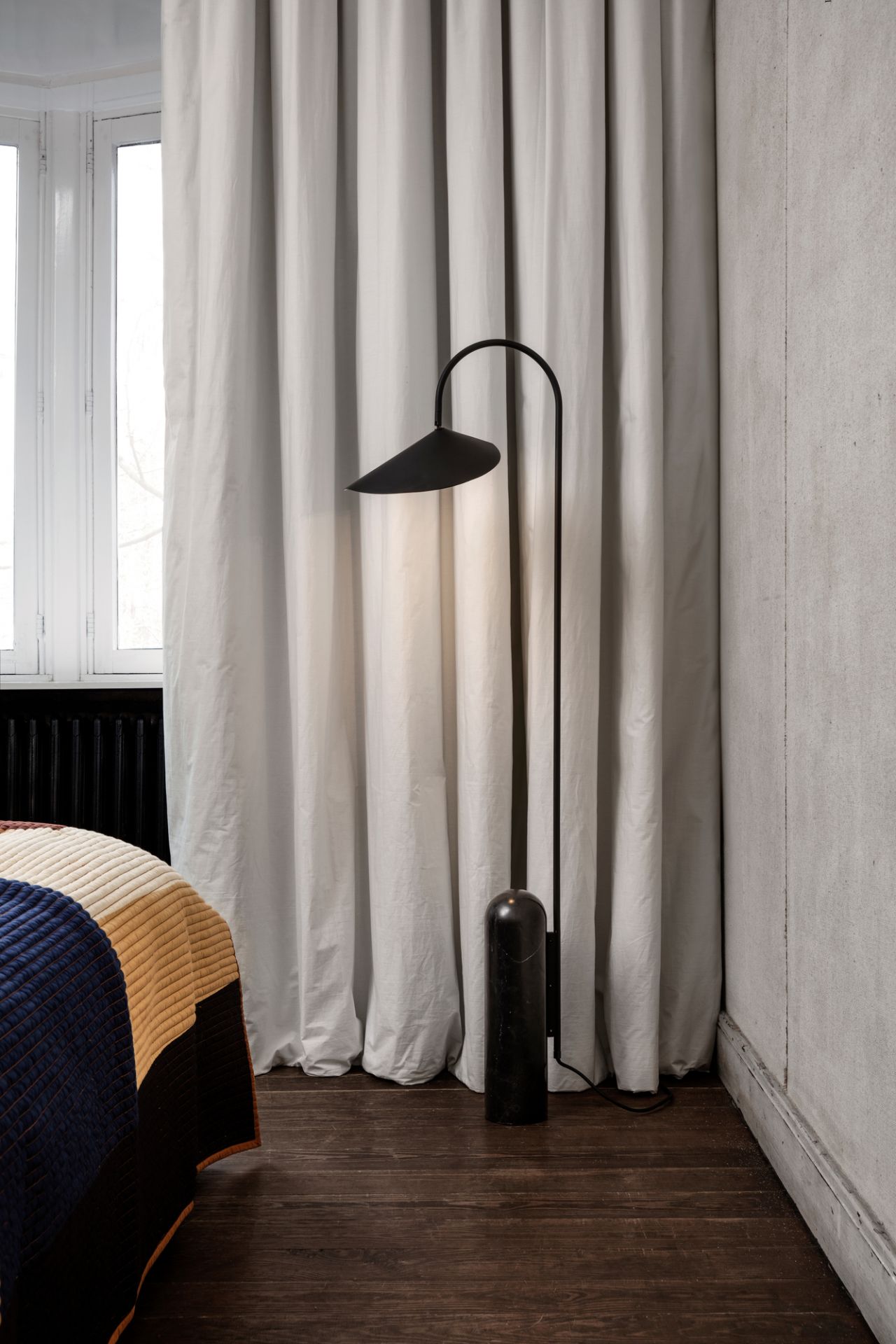 Schwarze Arum Stehlampe von Ferm Living mit schirmförmigem Lampenkopf und zylindrischem Fuß.