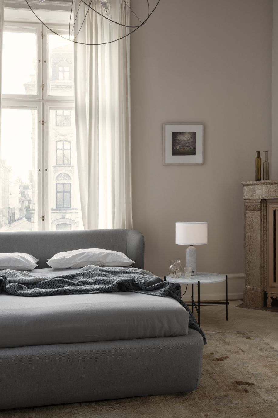 Gravity Tischleuchte Small von Gubi mit weißem Canvas Schirm und Marmorfuß auf Nachttisch.