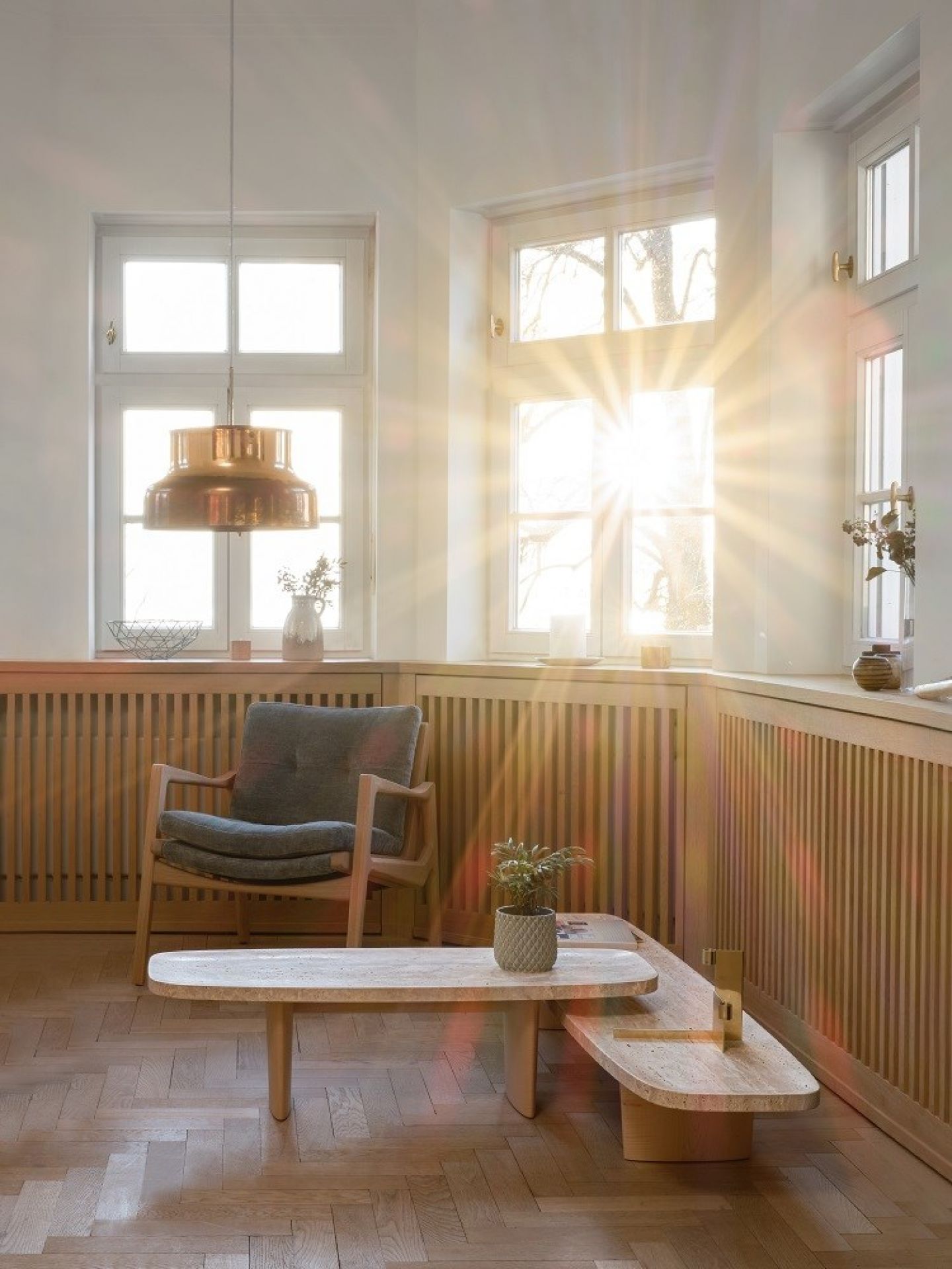 Heller Raum mit Classicon Couchtisch Matéria, Sessel und Parkettboden im modernen Design.