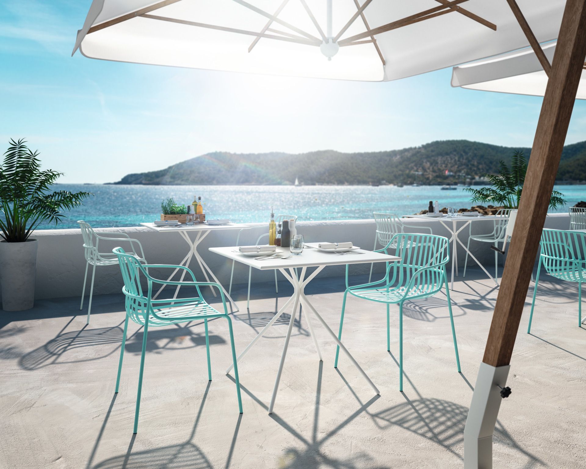 Quadratischer Brunner Bistrotisch aus Stahl für den Außenbereich auf einer Terrasse mit Meerblick.