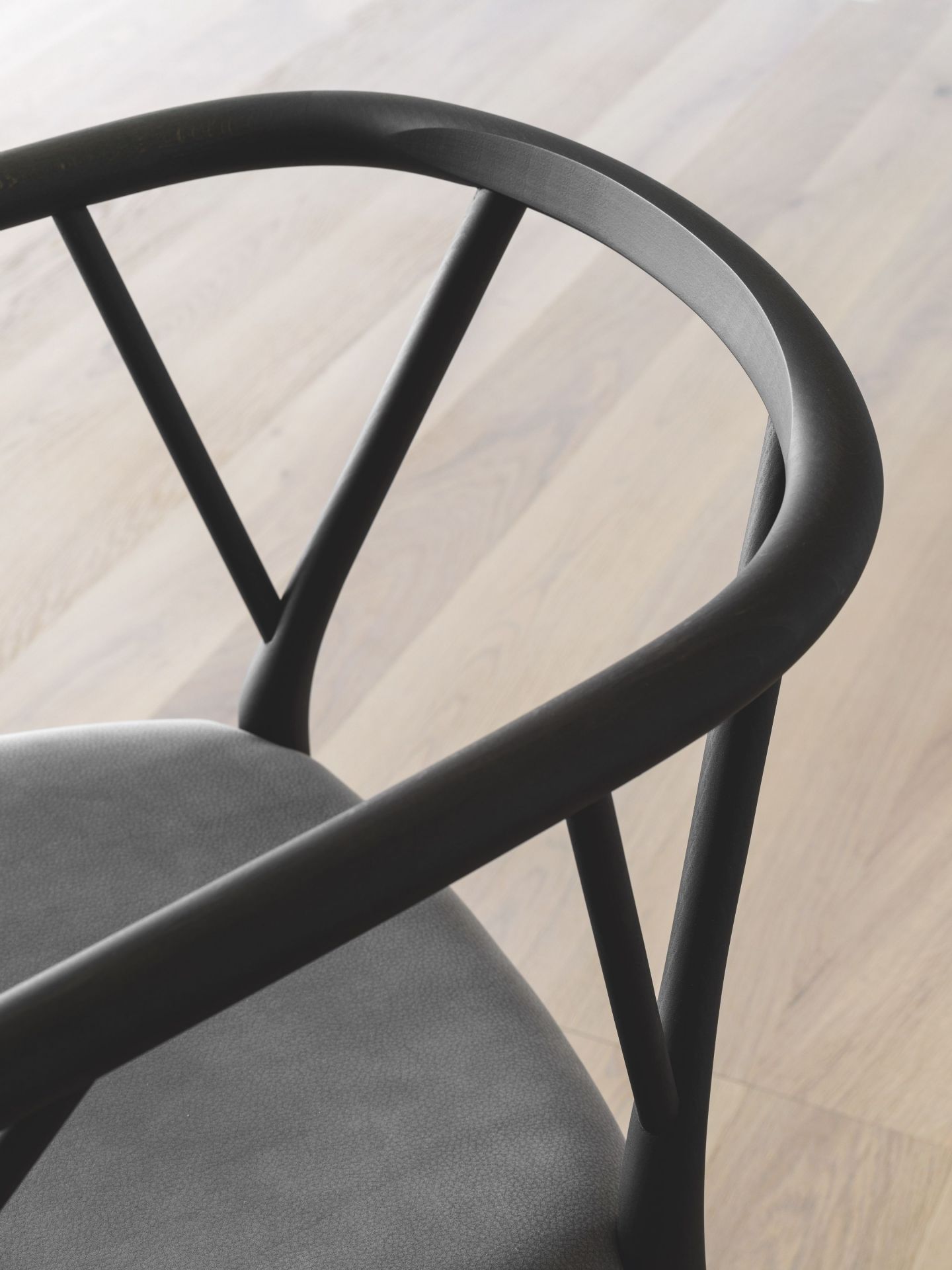 Detailaufnahme des Miniforms Valerie Stuhls mit Armlehne, modernes Design mit grauem Sitzpolster und dunklem Holzrahmen.