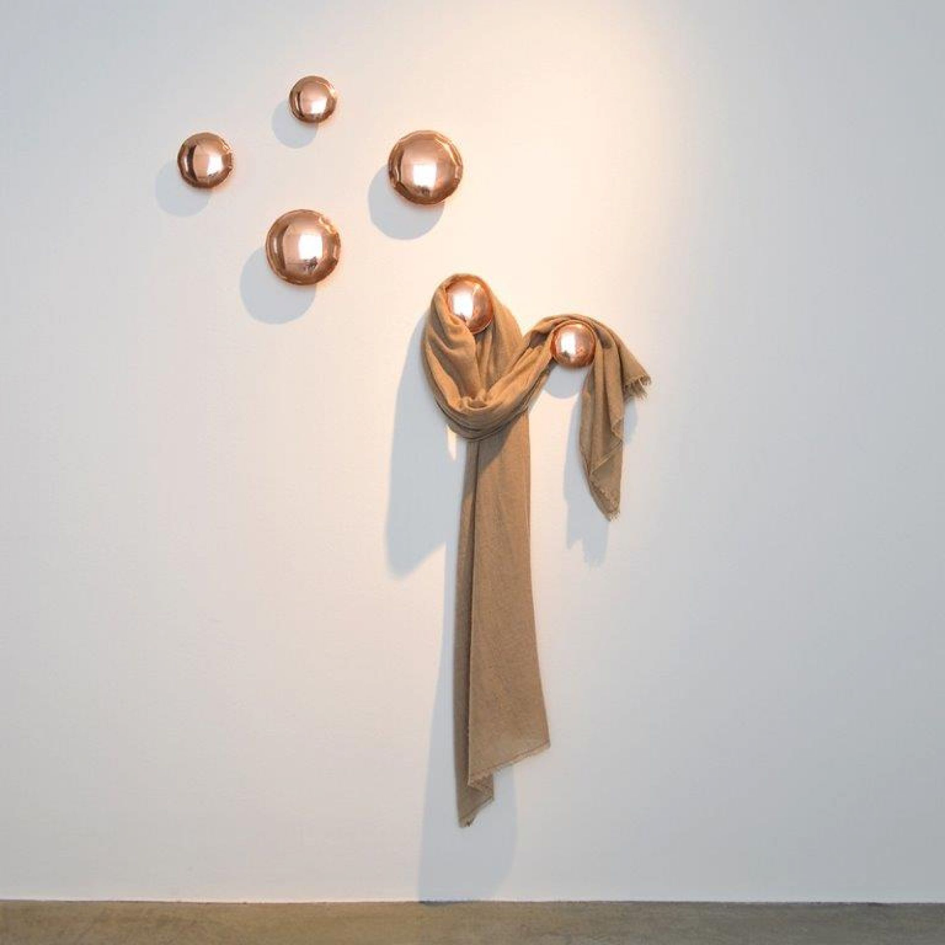 Wand mit fünf Pins Garderobenhaken in Kupferoptik, zwei mit Schal behangen. Design Garderobe von Zieta.