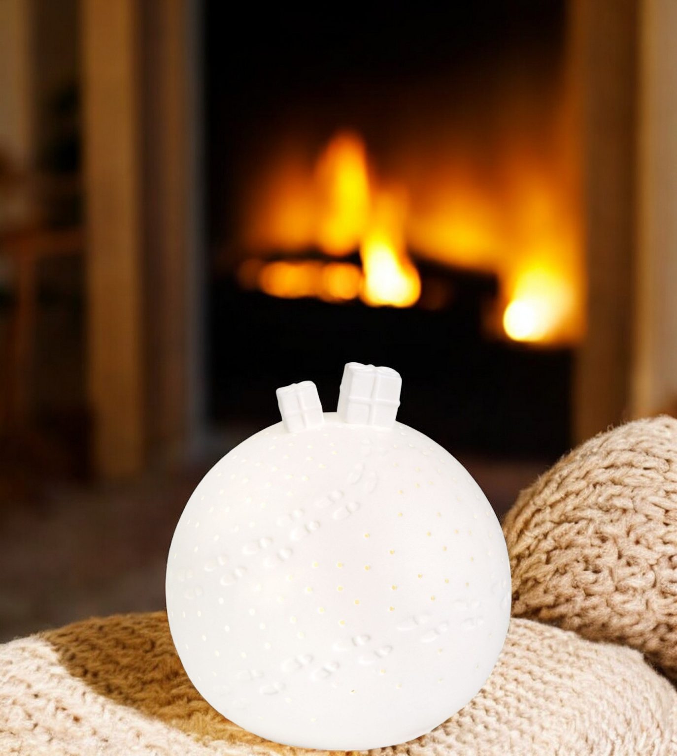 Weiße Porzellan Lichtkugel mit LED-Beleuchtung und Geschenk-Design vor Kaminfeuer. Einzigartiges Einzelstück.