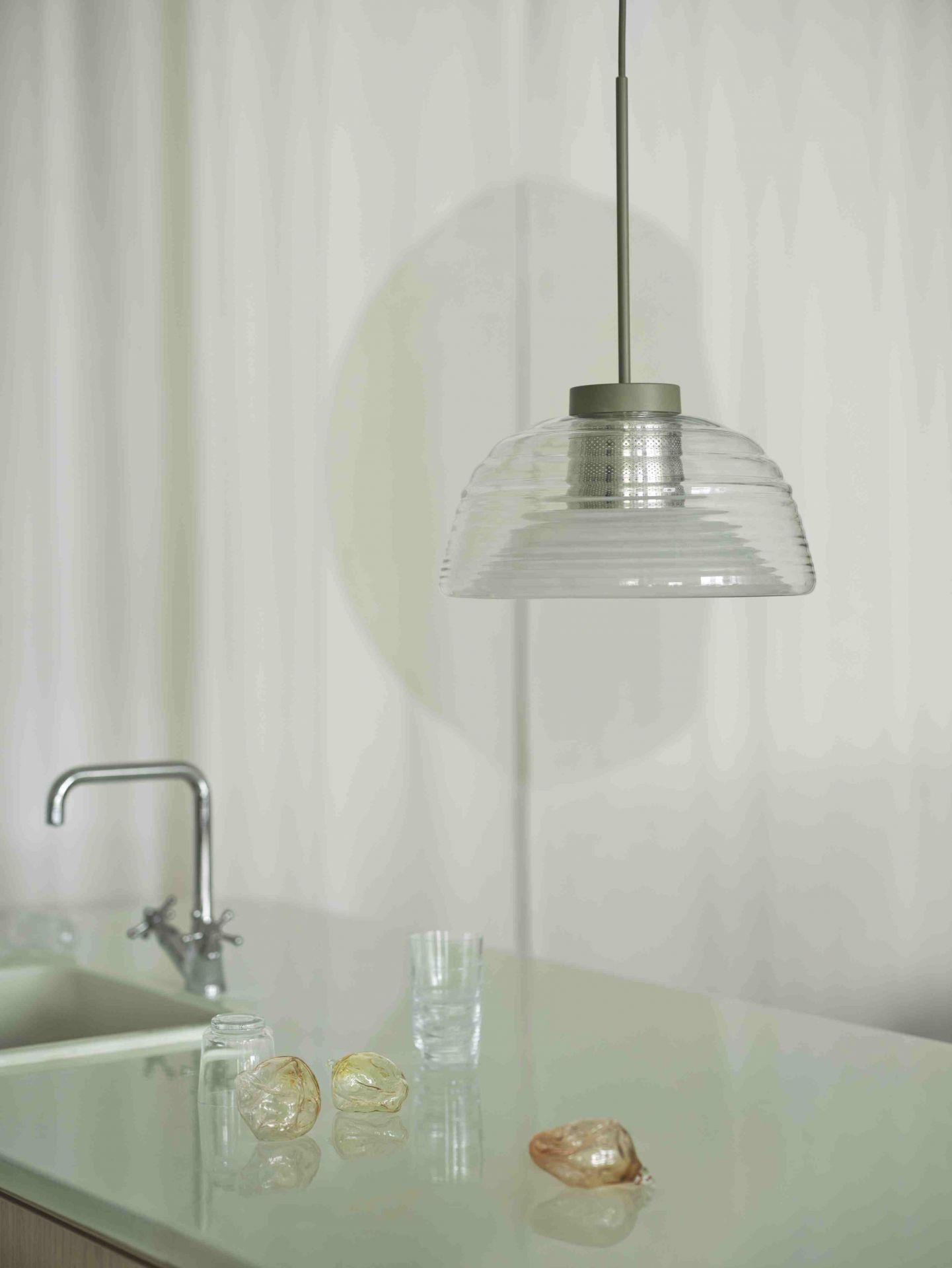 Muuto Two-Layer Pendelleuchte aus Glas hängt über einer modernen Küchentheke.