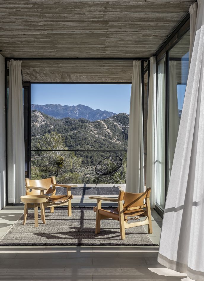 Telares Teppich Pine von Nanimarquina im modernen Wohnzimmer mit Holzmöbeln und Bergblick. Grauer Designer Teppich.