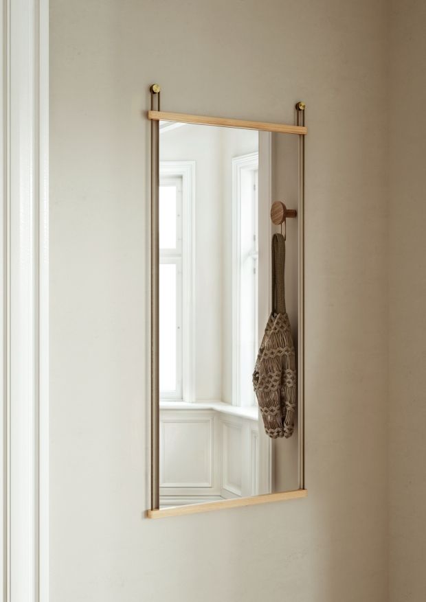 Rechteckiger Wandspiegel "Suspended Mirror Large" von Woud mit Holzrahmen und Haken, an beiger Wand.