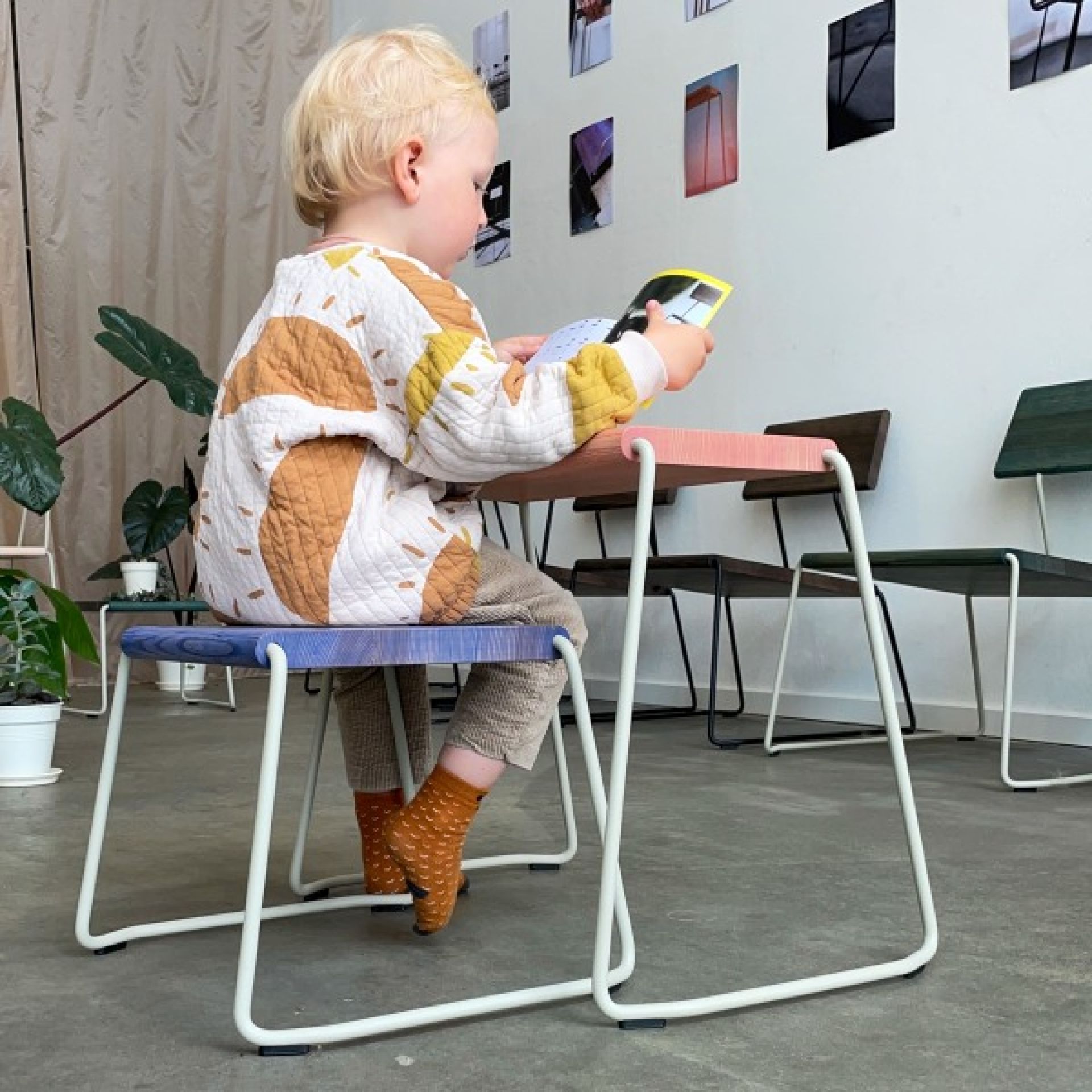 Kind sitzt auf blauem D:003 Beistellhocker von Fuchs & Habicht und liest ein Buch.