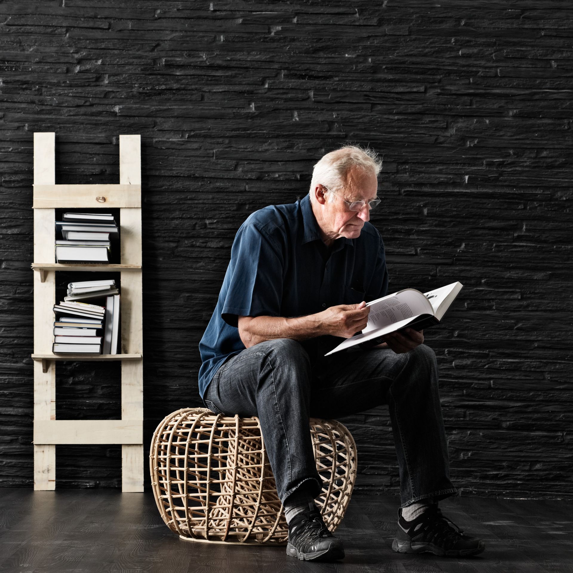 Mann liest Buch auf Nest Indoor Hocker von Cane-Line, Rattan Optik, gemütliches Wohnen.