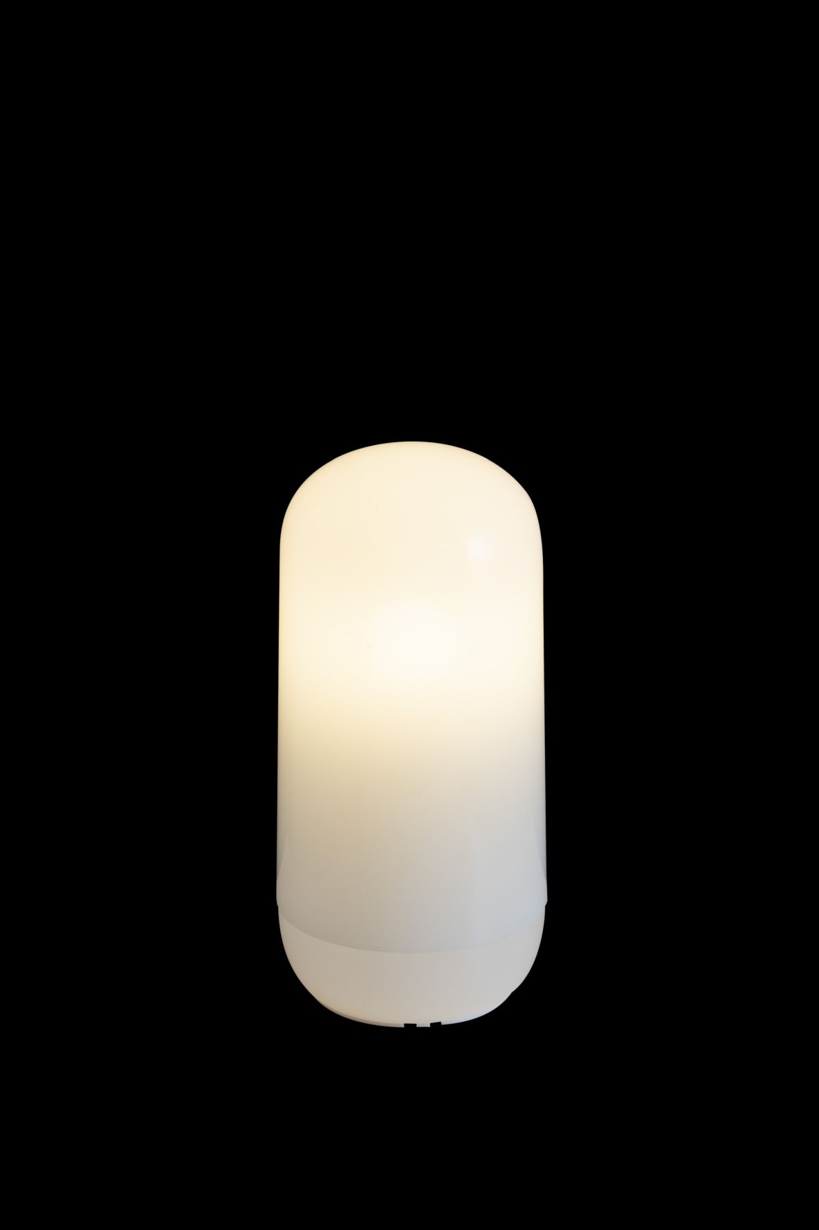 Nahaufnahme der leuchtenden, weißen Gople Akkuleuchte von Artemide auf schwarzem Hintergrund.