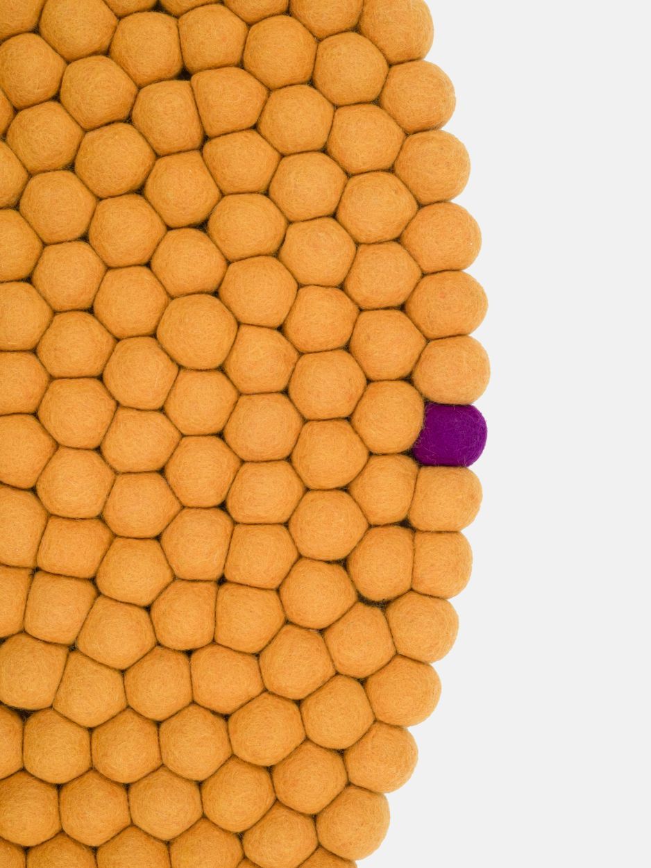 Detailaufnahme: Ockergelber myfelt Filzteppich aus vielen Filzkugeln, ein Hingucker für jeden Raum.