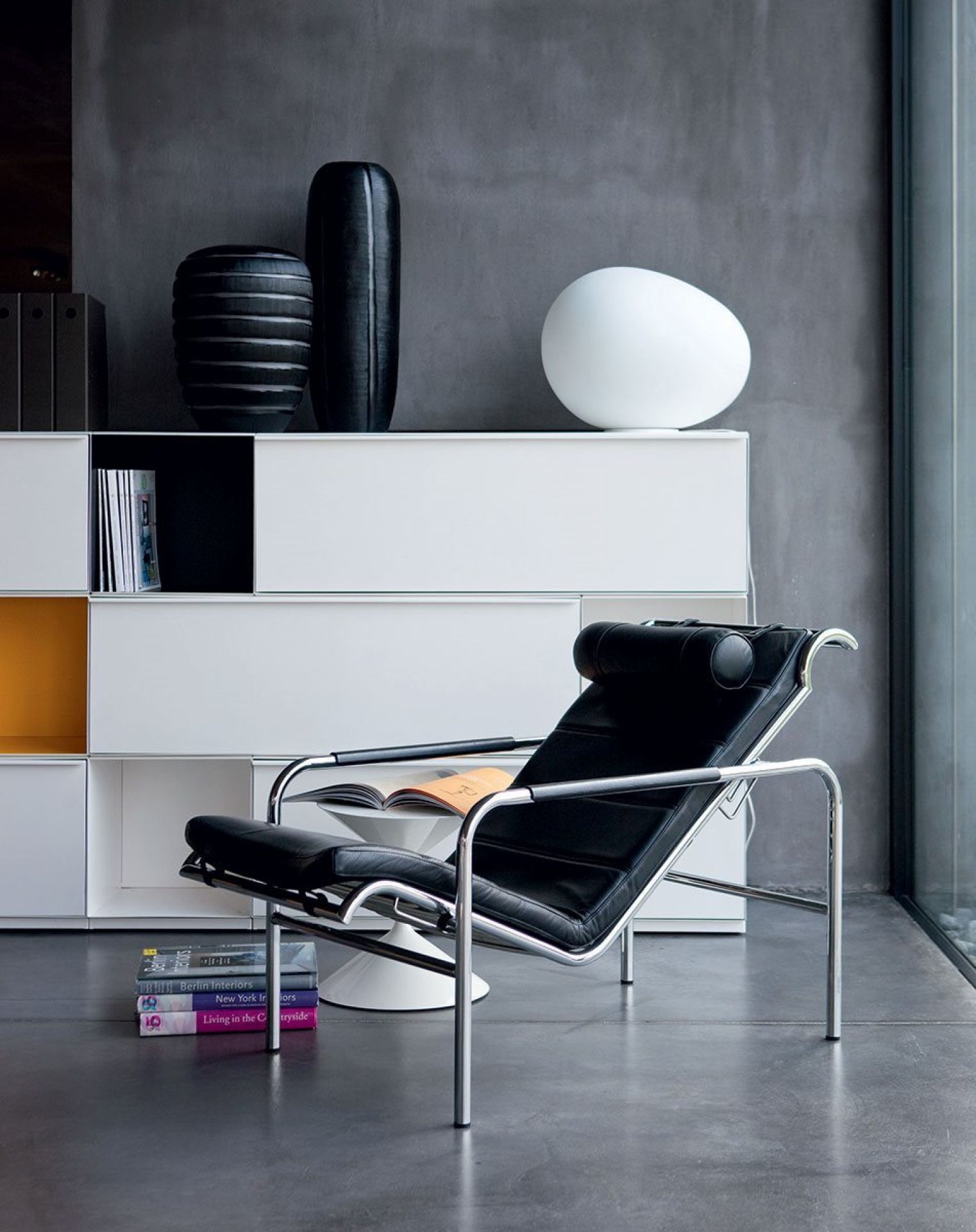 Schwarze Genni Chaiselongue von Zanotta mit verchromtem Gestell und Lederbezug im modernen Wohnzimmer.