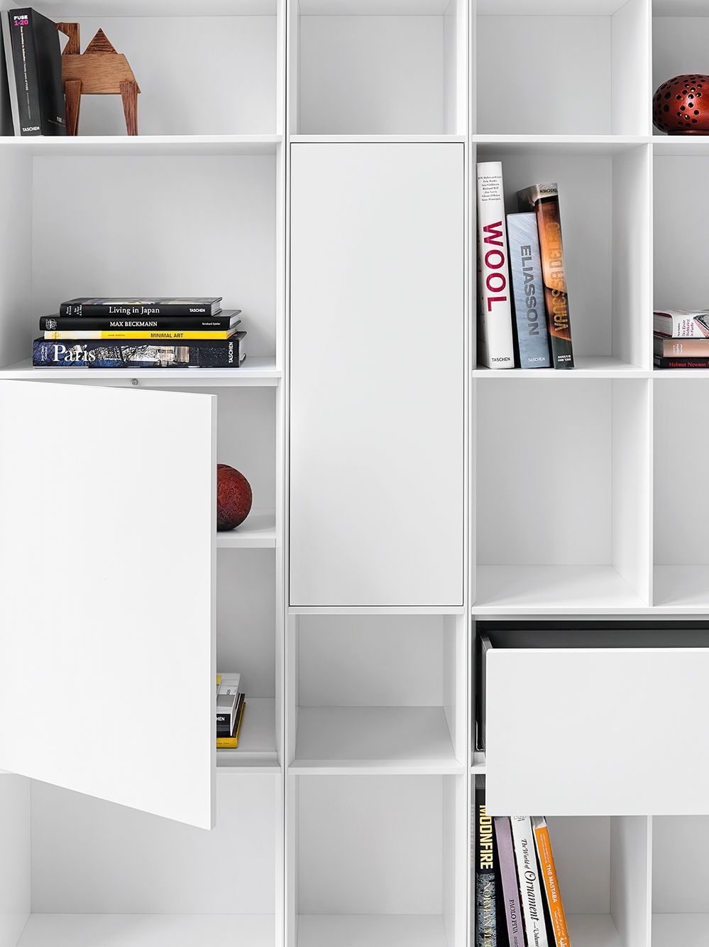 Detailaufnahme: Weißes Nex Pur Regal mit Tür, Fachboden und diversen Deko-Objekten.