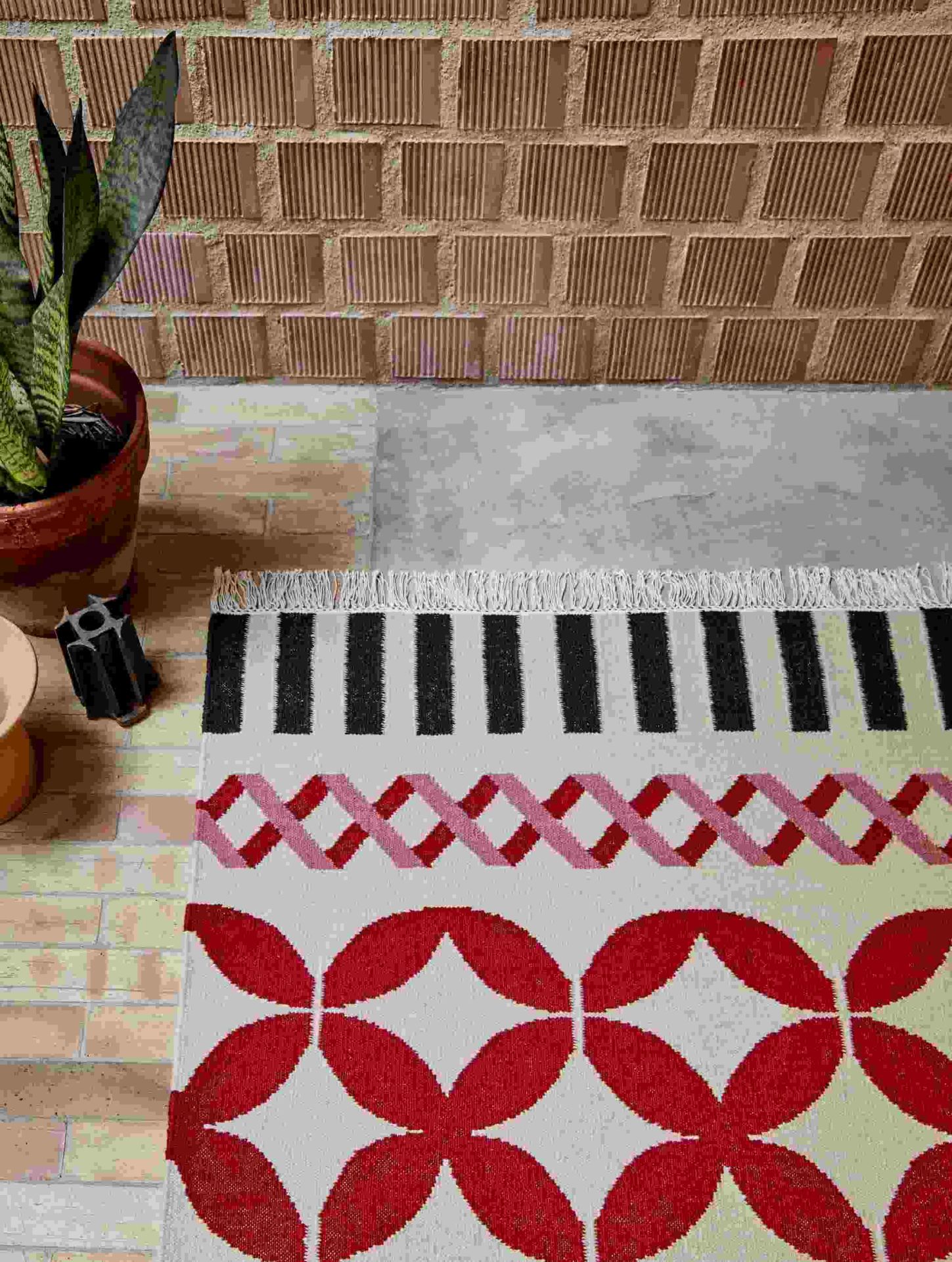 Detailaufnahme des Kilim Catania Teppichs mit geometrischen Mustern in Rot, Rosa und Schwarz.
