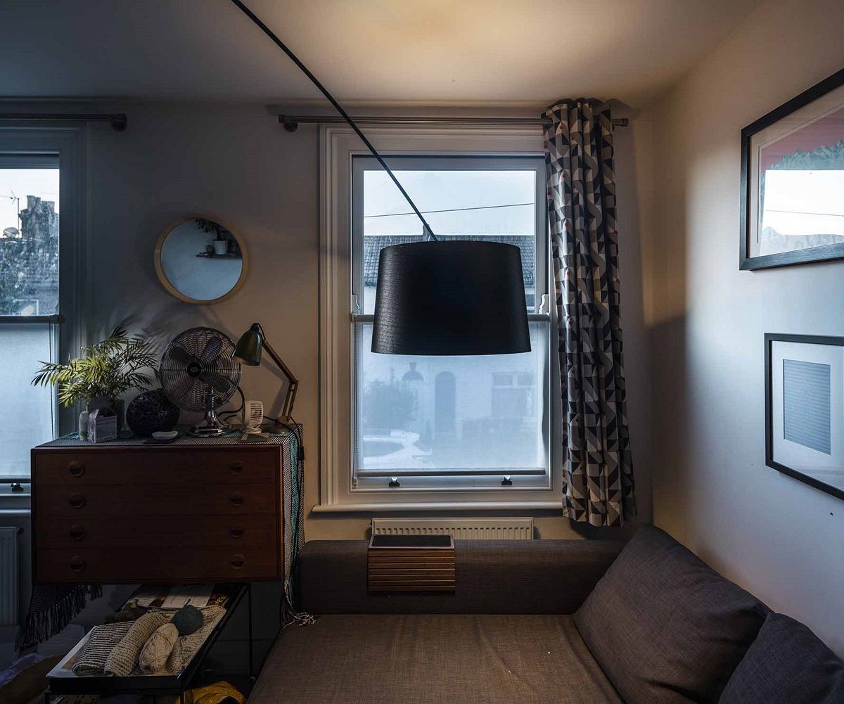 Schwarze Twiggy Soffitto Deckenleuchte von Foscarini hängt über einem grauen Sofa in einem gemütlichen Wohnzimmer.