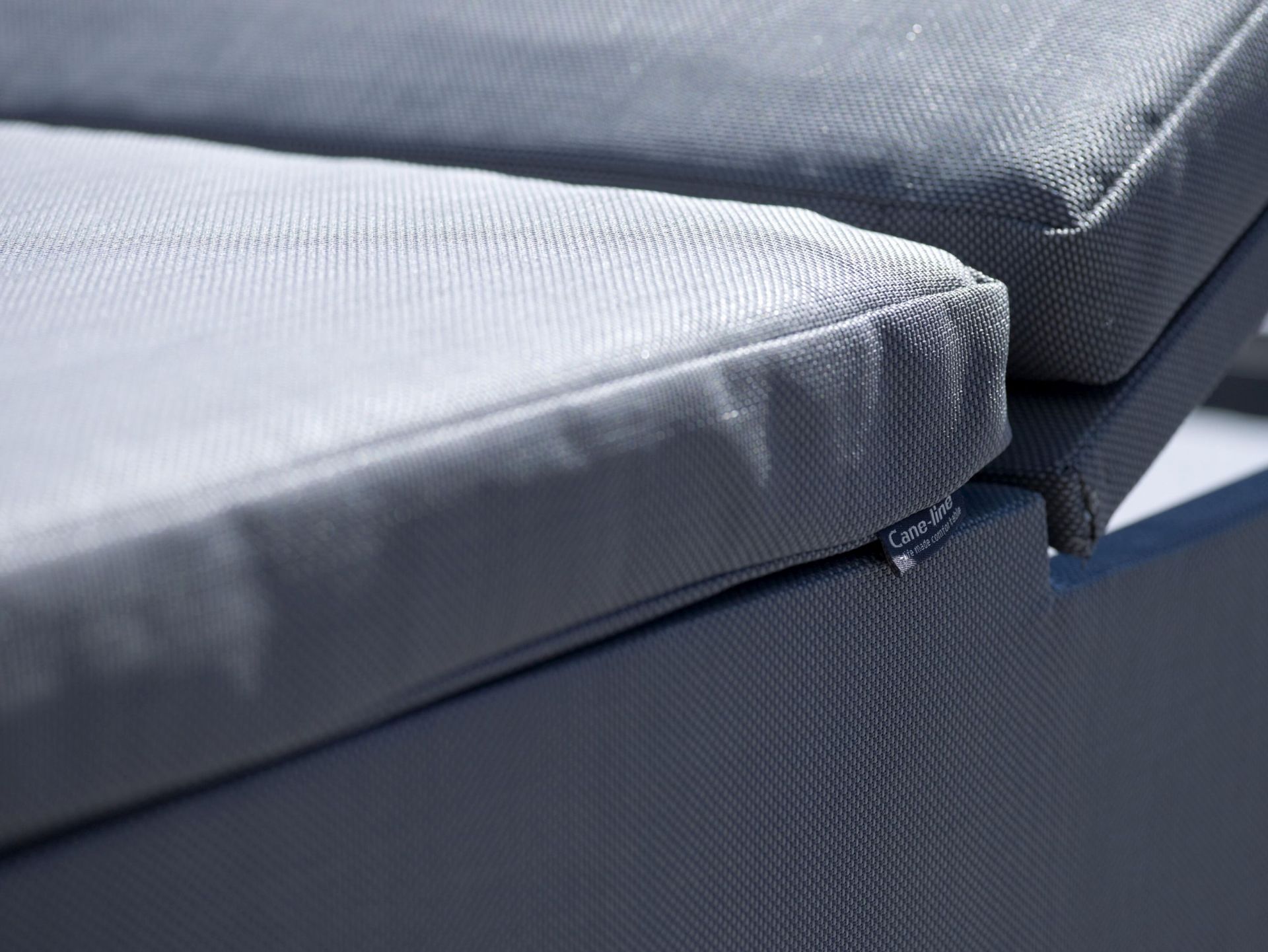 Nahaufnahme einer grauen Cane-Line Sonnenliege mit bequemen Polstern für den Außenbereich.