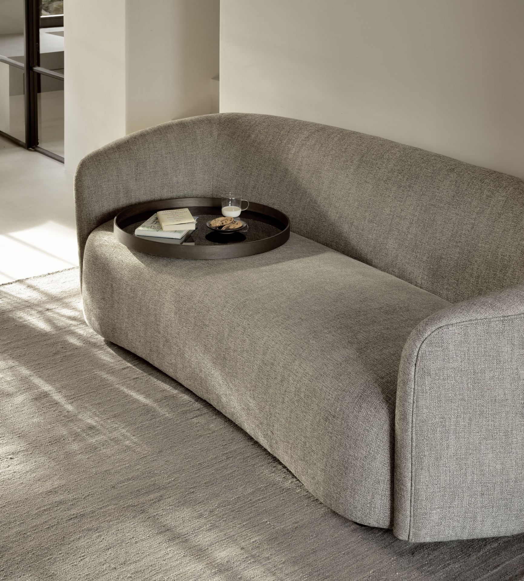 Ellipse Sofa 3-Sitzer von Ethnicraft in Grau mit Tablett, Buch, Milch und Keksen.