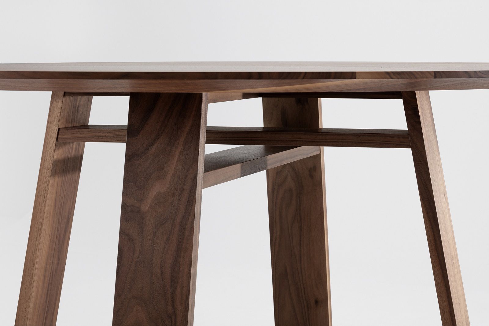 Detailaufnahme des BONDT Tisches: Runder Holztisch mit einzigartigem Untergestell aus massivem Nussbaumholz.