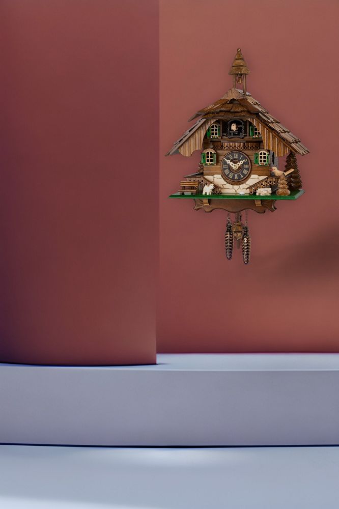 Detailaufnahme einer Engstler Kuckucksuhr mit Holzhaus-Design, Ziffernblatt und Pendel. Dekorative Schwarzwald Kuckucksuhr.