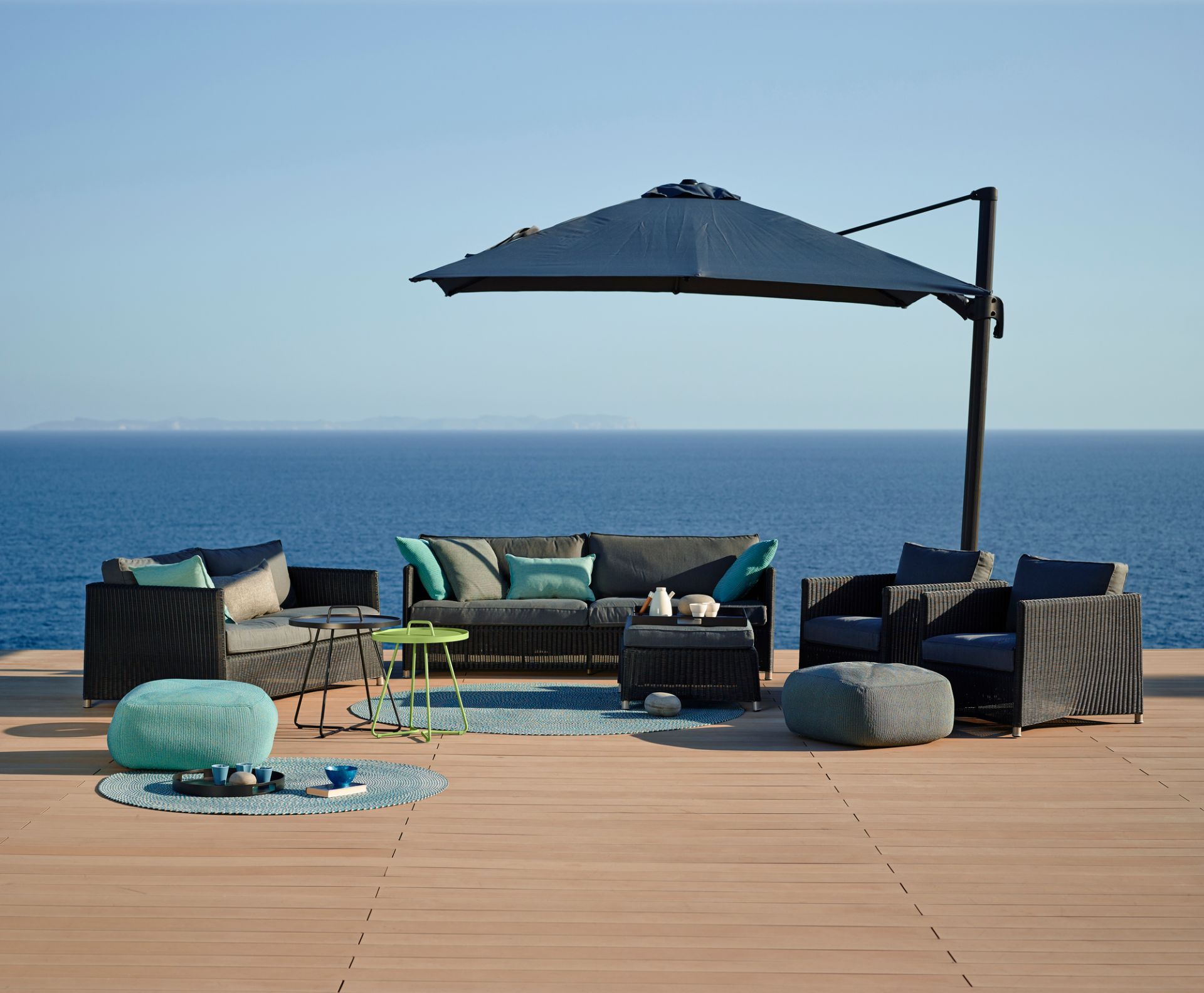 Diamond Hocker von Cane-Line als Teil einer stilvollen Outdoor-Lounge mit Meerblick.