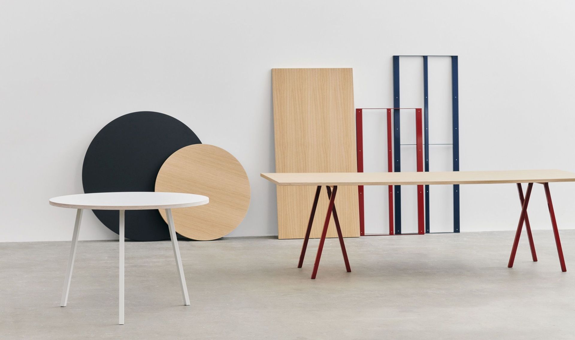 Hay Loop Stand Table Esstisch mit rotem Gestell und weiteren Möbeln im Hintergrund.