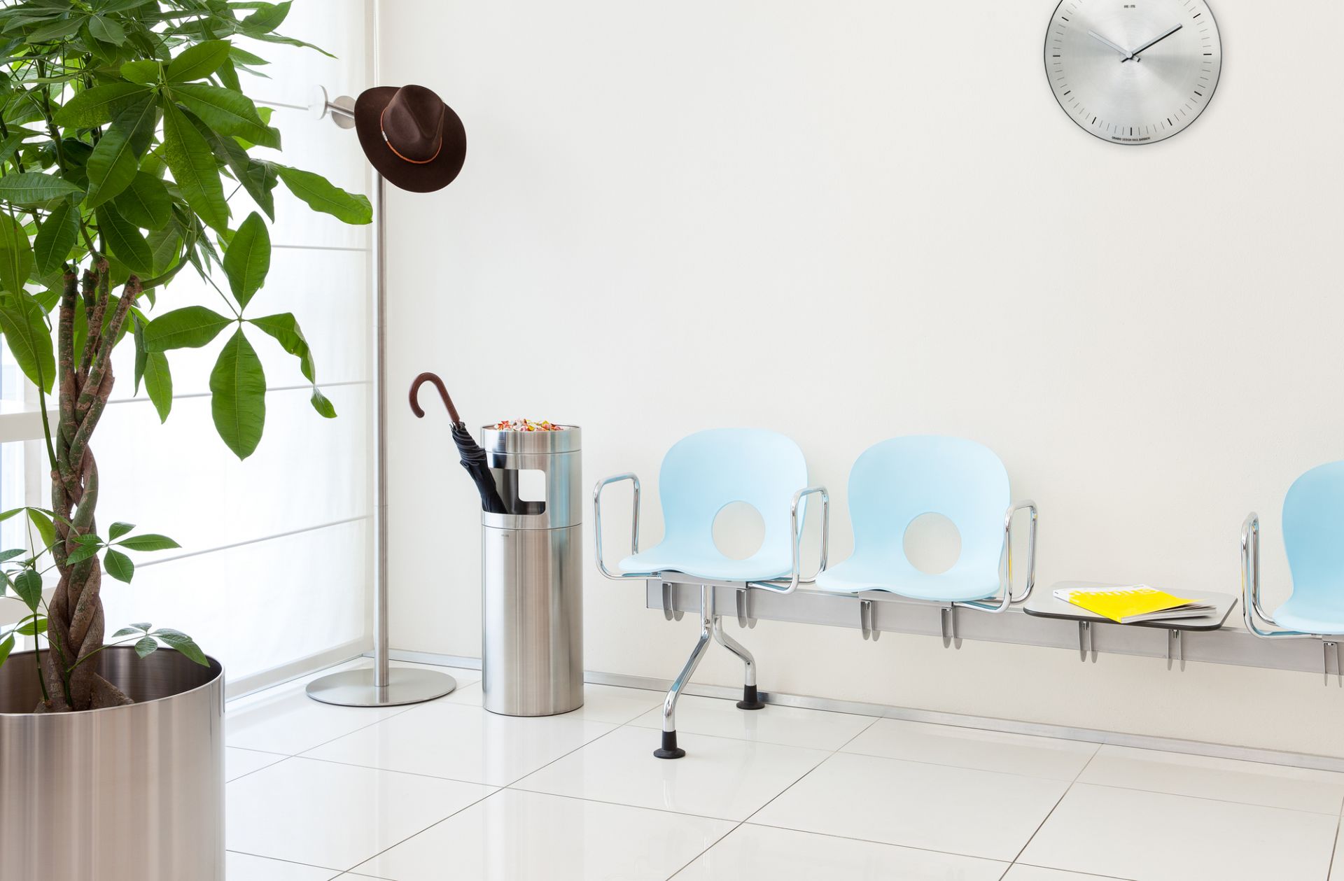 Helle Wartebereich-Szene mit Orario Wanduhr, Edelstahl, ohne Ziffernblatt, modernes Design.