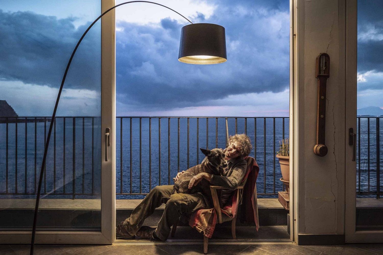 Twiggy LED Stehleuchte von Foscarini in Schwarz beleuchtet Mann mit Hund auf Balkon.