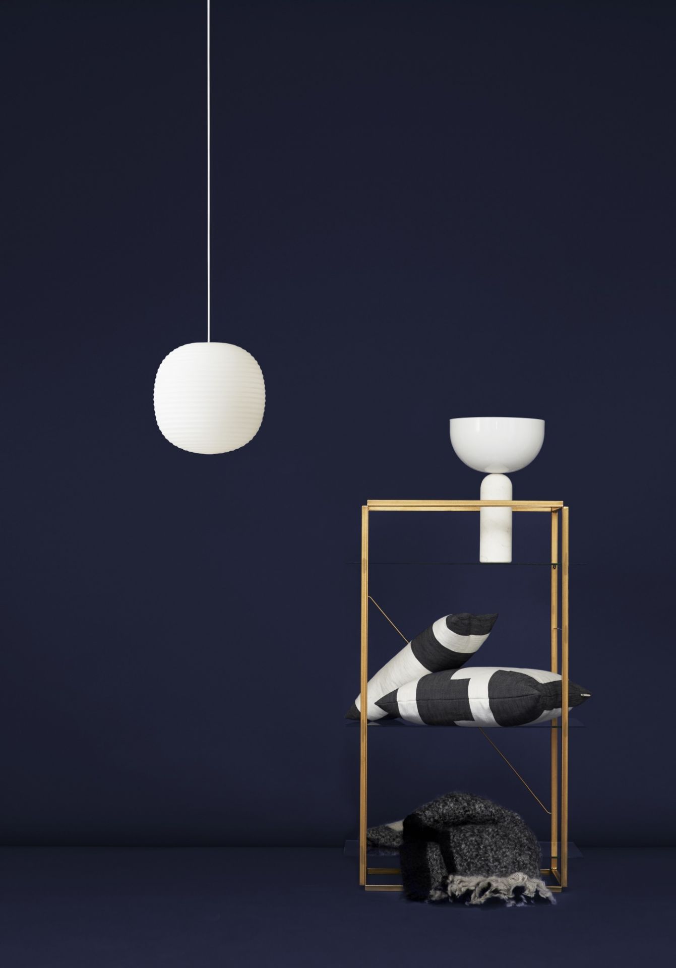 Weiße Kizu Tischleuchte von New Works auf einem Regal, moderne Wohnraumleuchte für Nachttisch oder Sideboard.