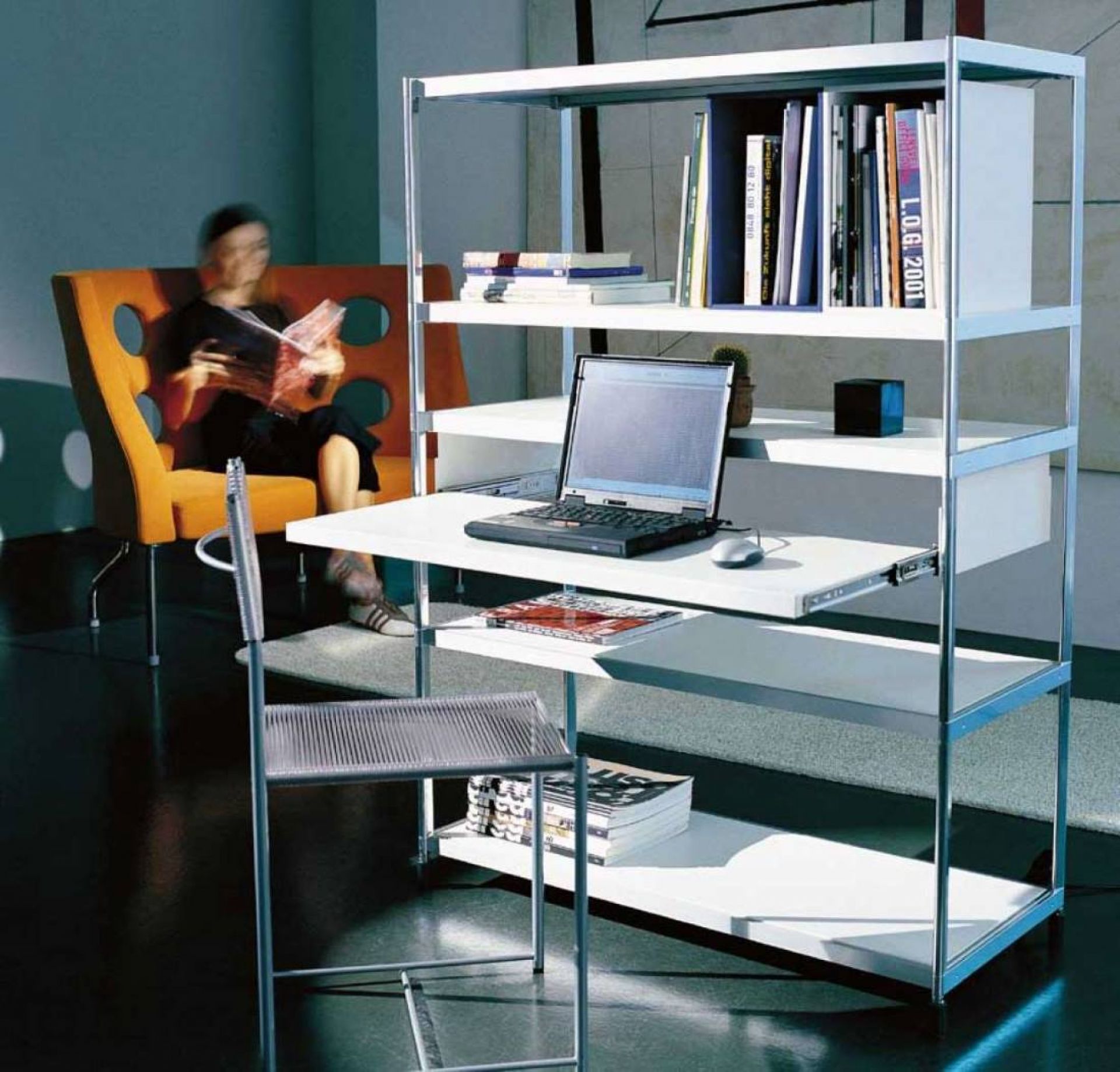 Spaghetti Chair Stuhl Alias vor Regal mit Laptop und lesender Person im Hintergrund.