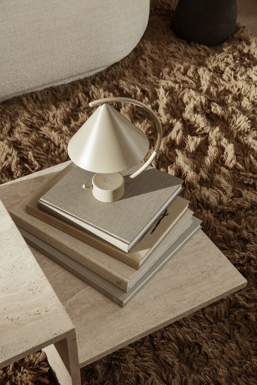 Meridian Lampe von Ferm Living in Cashmere auf einem Stapel Bücher auf einem Tisch.