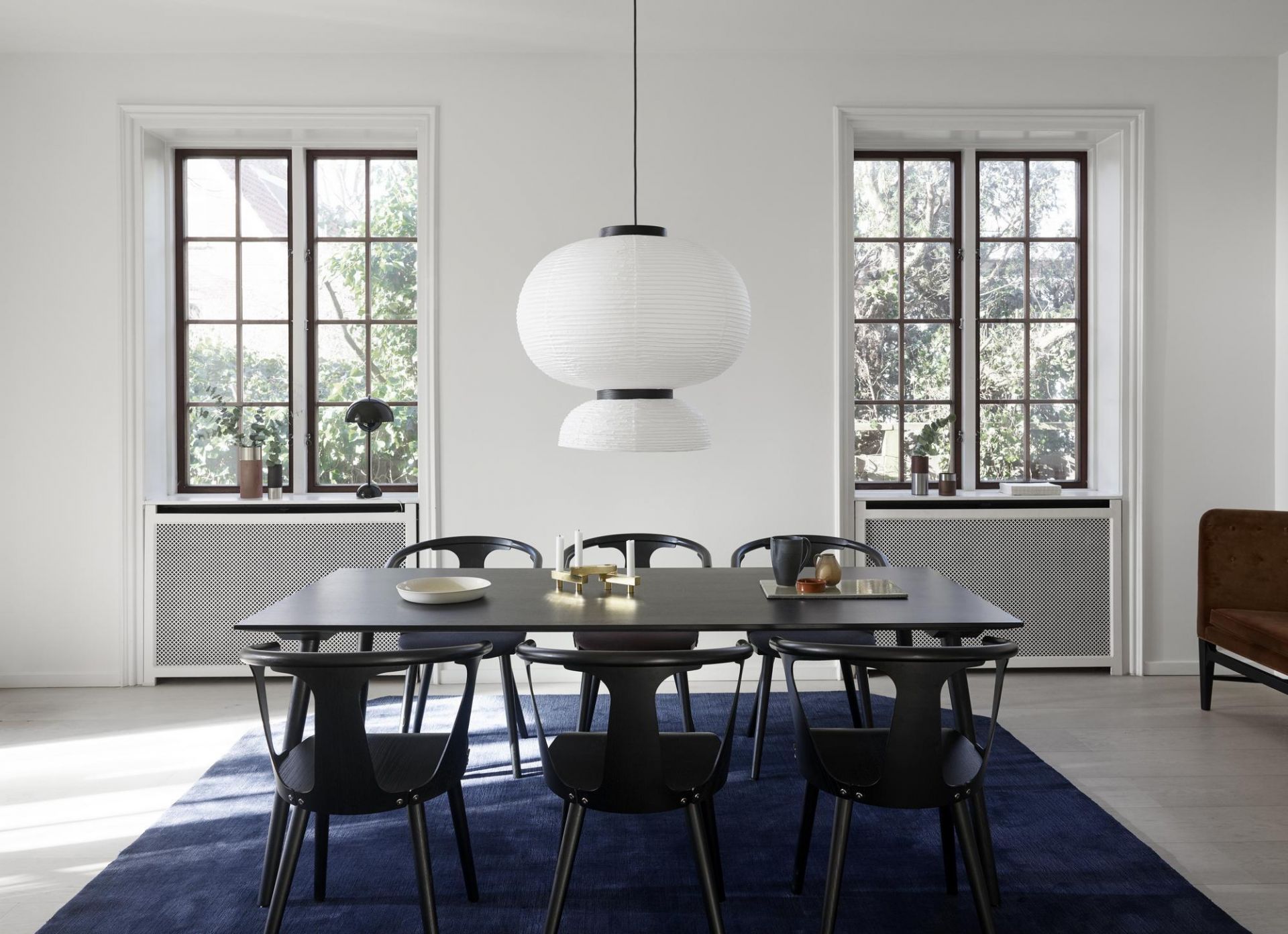 Formakami JH5 Hängeleuchte von AndTradition über Esstisch mit Stühlen und blauem Teppich.