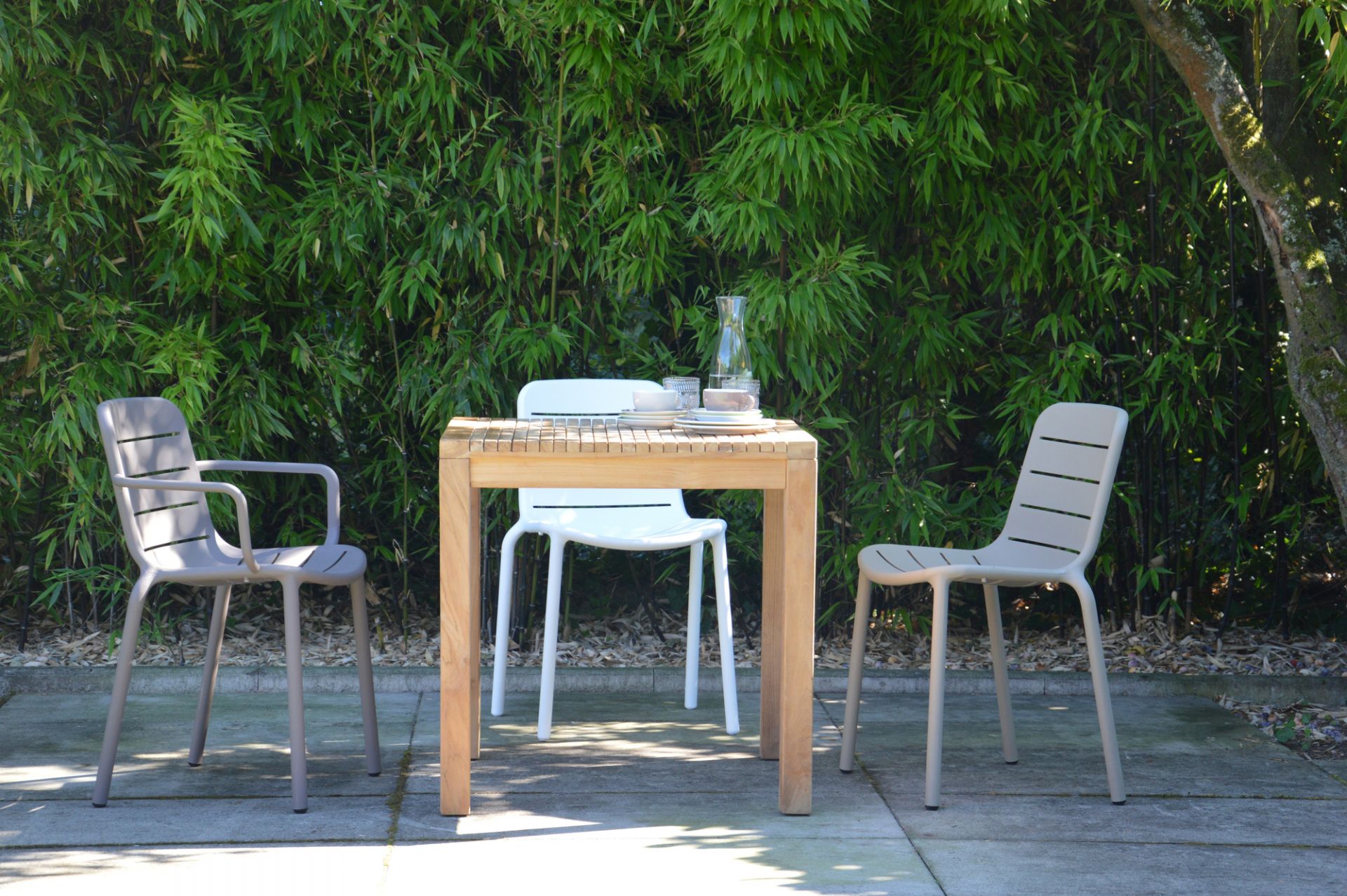 Samoa Tisch Natur von Jan Kurtz mit Geschirr und Stühlen im Garten. Gartentisch aus Holz.