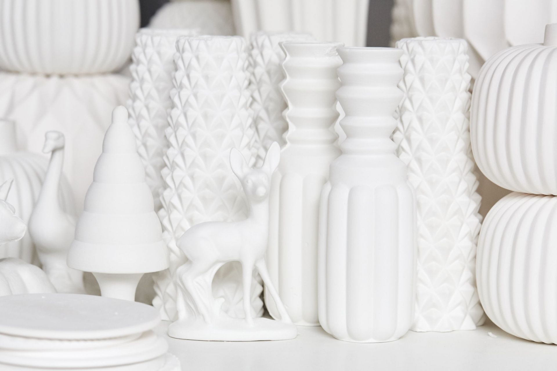 Winterliche Deko: Weißes Rehkitz als Teelichthalter von Dottir, umgeben von Vasen und Weihnachtsbaum-Figur.