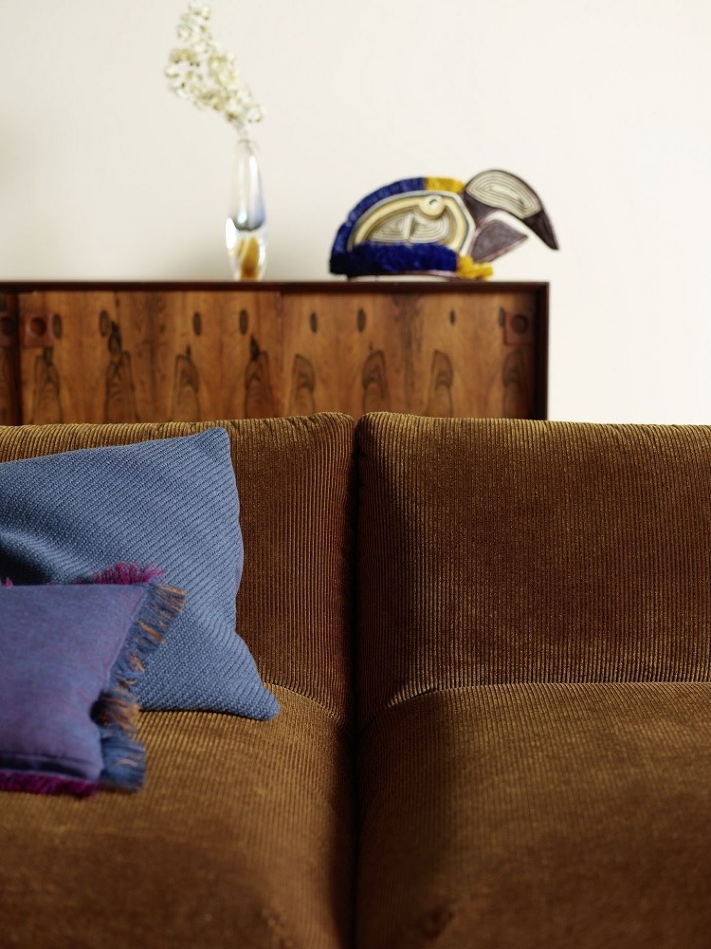 Detailaufnahme Jalis21 Sofa mit Cordbezug in Bernstein, inklusive blauer Zierkissen.